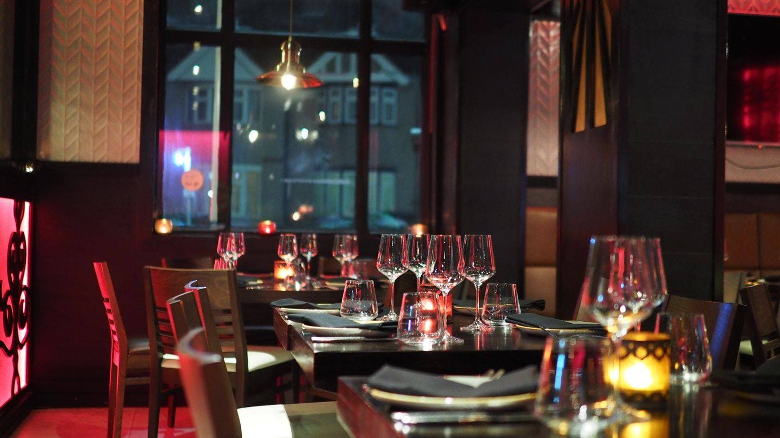 Evening dining room with set tables, wine glasses, and candlelight, used as the restaurant concept preview.